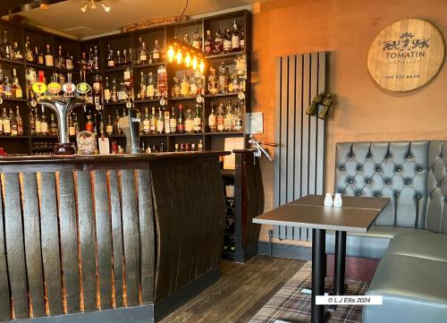 a bar with a shelf of liquor bottles at Foyers House in Foyers