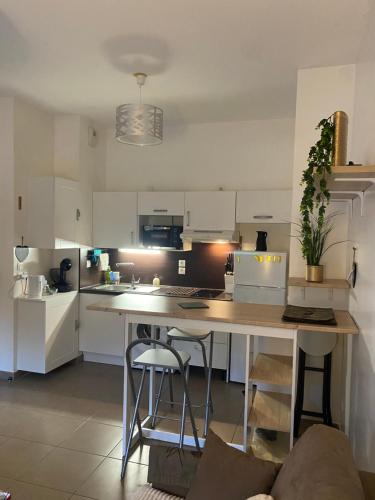 une cuisine avec des armoires blanches et une table avec des tabourets dans l'établissement Pornichet 3 mns de la plage avec jardin classé 3 étoiles, à Pornichet