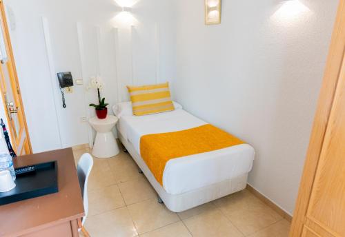 a small bedroom with a bed and a desk at Hostal Josefina-Gran Vía in Madrid