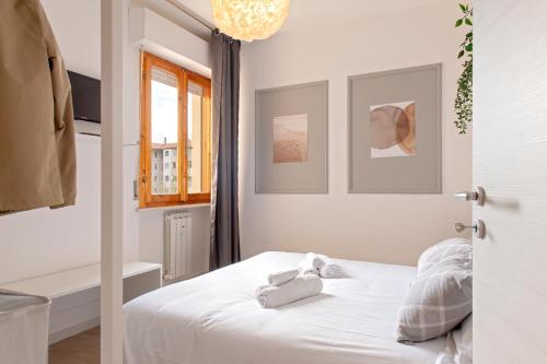 Un dormitorio con una cama blanca con toallas. en Homiday- New Apt- Free Parking- Aeroporto - Ospedale en Pisa