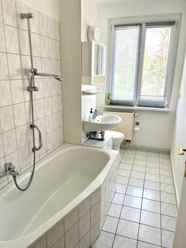 ein weißes Badezimmer mit einer Badewanne und einem Waschbecken in der Unterkunft Große Monteurwohnung in Spremberg