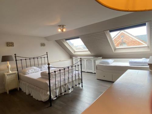 a bedroom with two beds and two windows at Ruim herenhuis met grote tuin op 5min van zee - 8p in Middelkerke