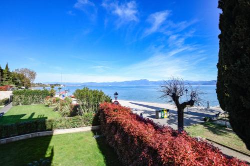 a view of the water from a park with flowers at DOLCERIVA - The Lakefront Suite in Peschiera del Garda