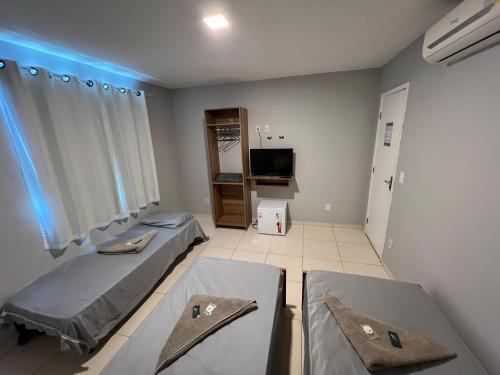 a hospital room with two beds and a tv at DLUX Hotel in Campos dos Goytacazes