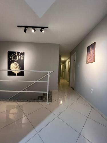 a hallway with a white tile floor and paintings on the wall at DLUX Hotel in Campos dos Goytacazes