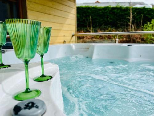 three wine glasses sitting on a table in a hot tub at Artro Lodge Luxury 3 Bedroom, 3 Bathroom & Hot Tub in Llanbedr