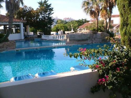 a swimming pool with blue water and palm trees at Apartamento en Cala en Porter Menorca in Cala en Porter