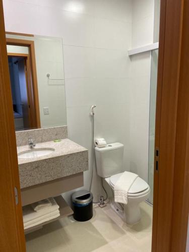 ein Badezimmer mit einem WC, einem Waschbecken und einem Spiegel in der Unterkunft Apartamento Lagoa Ecotowers resort in Caldas Novas