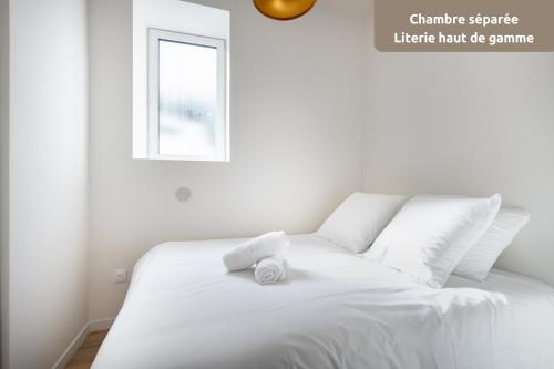 Una cama blanca con una toalla blanca encima. en ROMARIN * Lumineux * Linge hôtelier * Fibre * Confort, en La Destrousse