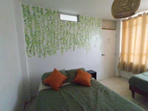 a living room with a green couch with orange pillows at Hostel Killamoon Centro in Paracas