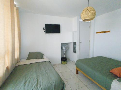 a bedroom with two twin beds and a tv at Hostel Killamoon Centro in Paracas