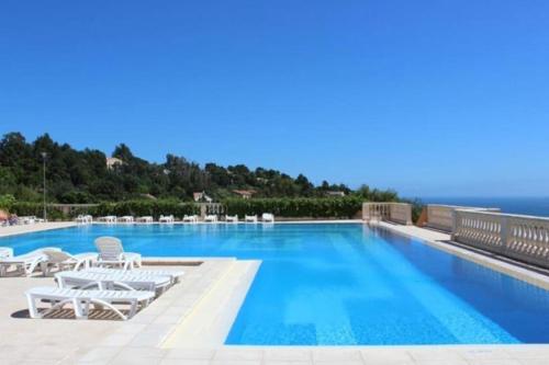 une piscine avec des chaises et l'océan en arrière-plan dans l'établissement Le Petit Bonheur - Location de vacances (Studio 4P), à Roquebrune-sur Argens
