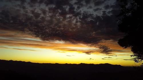 a sunset over a mountain range with the sun setting at Clorofila Hospedaria in São Bento do Sapucaí