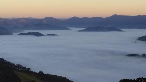 vista para um mar de nevoeiro com montanhas ao fundo em Clorofila Hospedaria em São Bento do Sapucaí