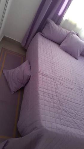 a bed with purple sheets and pillows in a room at Maison de vacances in Santo Domingo