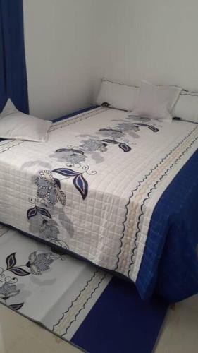 a bed with a blue and white blanket on it at Maison de vacances in Santo Domingo