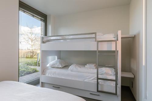 sypialnia z łóżkiem piętrowym i oknem w obiekcie Spacious holiday home with indoor pool & sauna w mieście Veurne