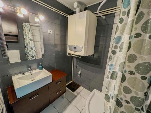baño con lavabo y cortina de ducha en MIHI APARTMAN, en Balatonvilágos