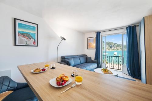 une table avec deux assiettes de nourriture et de jus d'orange dans l'établissement Les Sablettes - Cosy studio vue mer, vieux Menton, à Menton