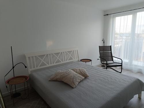 a white bedroom with a bed and two chairs at Słoneczny Apartament in Międzywodzie