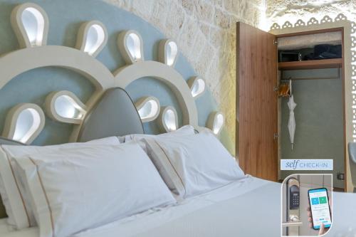 a bedroom with a bed with a large white headboard at Vico Bianco Raro Smart Rooms Collection in Ostuni