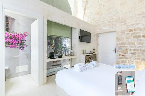 a white room with a bed and a tv at Vico Bianco Raro Smart Rooms Collection in Ostuni