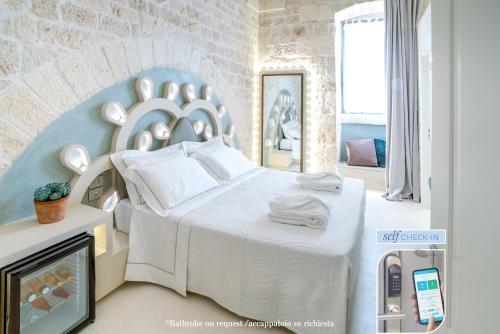 a bedroom with a large white bed and a fireplace at Vico Bianco Raro Villas Smart Rooms Collection in Ostuni