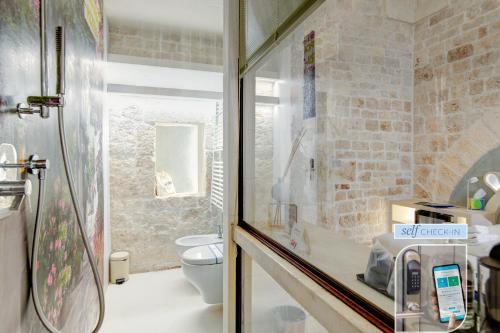 a bathroom with a toilet and a glass shower at Vico Bianco Raro Smart Rooms Collection in Ostuni