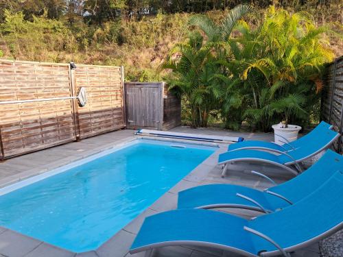 una piscina con sillas azules y una valla en Villa Mahi Mahi, en Les Trois-Îlets