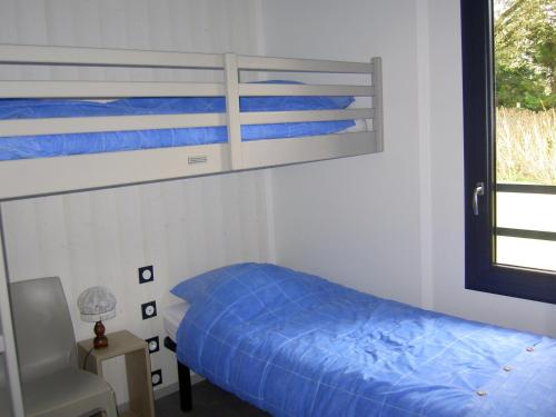 um quarto com um beliche com lençóis azuis e uma janela em Chalet Guérande, 3 pièces, 4 personnes - FR-1-783-17 em Guérande
