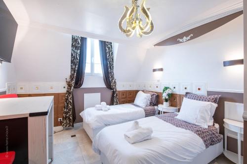 a bedroom with two beds and a chandelier at Studio Marron - Paris à 10 min - RER in Deuil-la-Barre