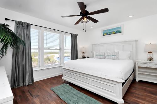 a bedroom with a white bed and a ceiling fan at Bucket List by Pristine Properties Vacation Rentals in Mexico Beach