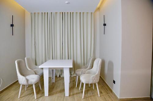 uma sala de jantar branca com uma mesa e cadeiras brancas em Golden House no Cairo