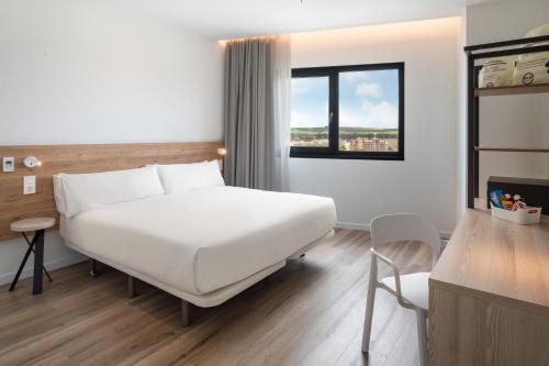 a bedroom with a large white bed and a window at B&B HOTEL Écija in Écija