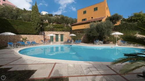 einen Pool mit Stühlen und Sonnenschirmen neben einem Gebäude in der Unterkunft Italianway - Il Borgo apartments in Finale Ligure