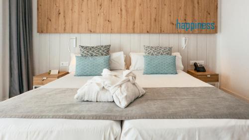 a bedroom with a large bed with white sheets and blue pillows at Labranda Corralejo Village in Corralejo