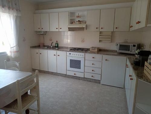een keuken met witte kasten en een fornuis met oven bij Apartamento en Cariño in Cariño