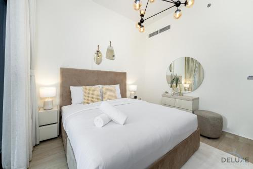 a white bedroom with a large bed and a mirror at Comfy 1BR in Azizi Riviera 8, Al Merkadh by Deluxe Holiday Homes in Dubai