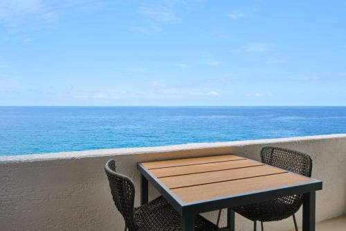 a table and chairs on a balcony overlooking the ocean at OUTRIGGER Kona Resort and Spa in Kailua-Kona