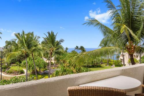 a balcony with a chair and palm trees and the ocean at OUTRIGGER Kona Resort and Spa in Kailua-Kona
