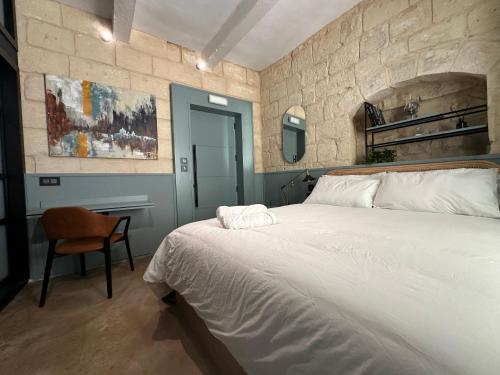 a bedroom with a large white bed and a chair at Felipe x Casa Norte in Birgu
