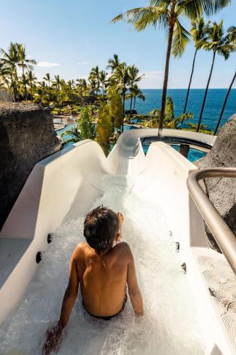 a shirtless man riding a water slide at a resort at OUTRIGGER Kona Resort and Spa in Kailua-Kona
