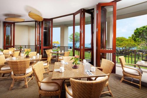 a restaurant with tables and chairs and large windows at OUTRIGGER Kona Resort and Spa in Kailua-Kona