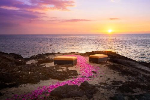 two beds on the beach with the sunset in the background at OUTRIGGER Kona Resort and Spa in Kailua-Kona