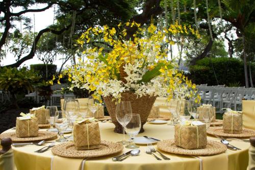 a table with yellow flowers in a vase on it at OUTRIGGER Kona Resort and Spa in Kailua-Kona