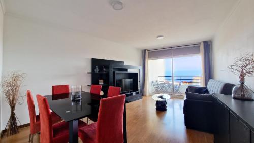 a living room with a dining room table with red chairs at Azenha Apartment by LovelyStay in Caniço