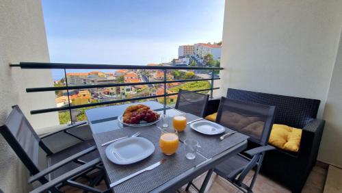 a table with a bowl of fruit and two glasses of orange juice at Azenha Apartment by LovelyStay in Caniço