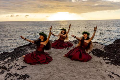 a group of four women sitting on a rock by the ocean at OUTRIGGER Kona Resort and Spa in Kailua-Kona