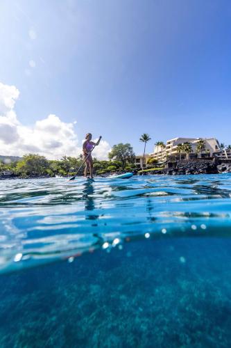 a man is paddle boarding in the water at OUTRIGGER Kona Resort and Spa in Kailua-Kona