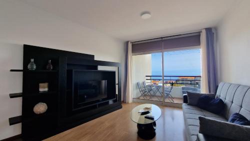 a living room with a couch and a television at Azenha Apartment by LovelyStay in Caniço